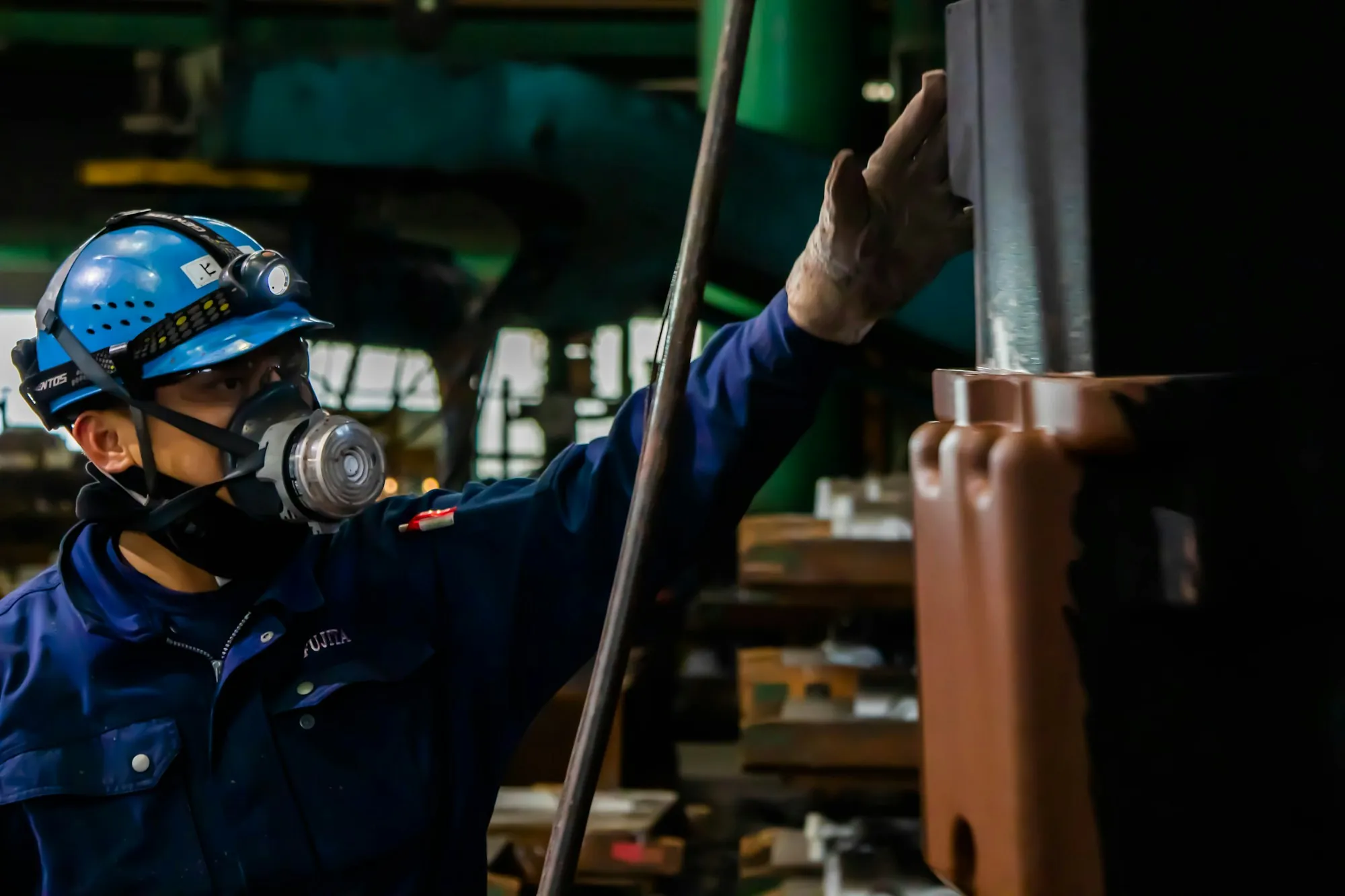 Worker in a respirator inspecting overhead in a plant