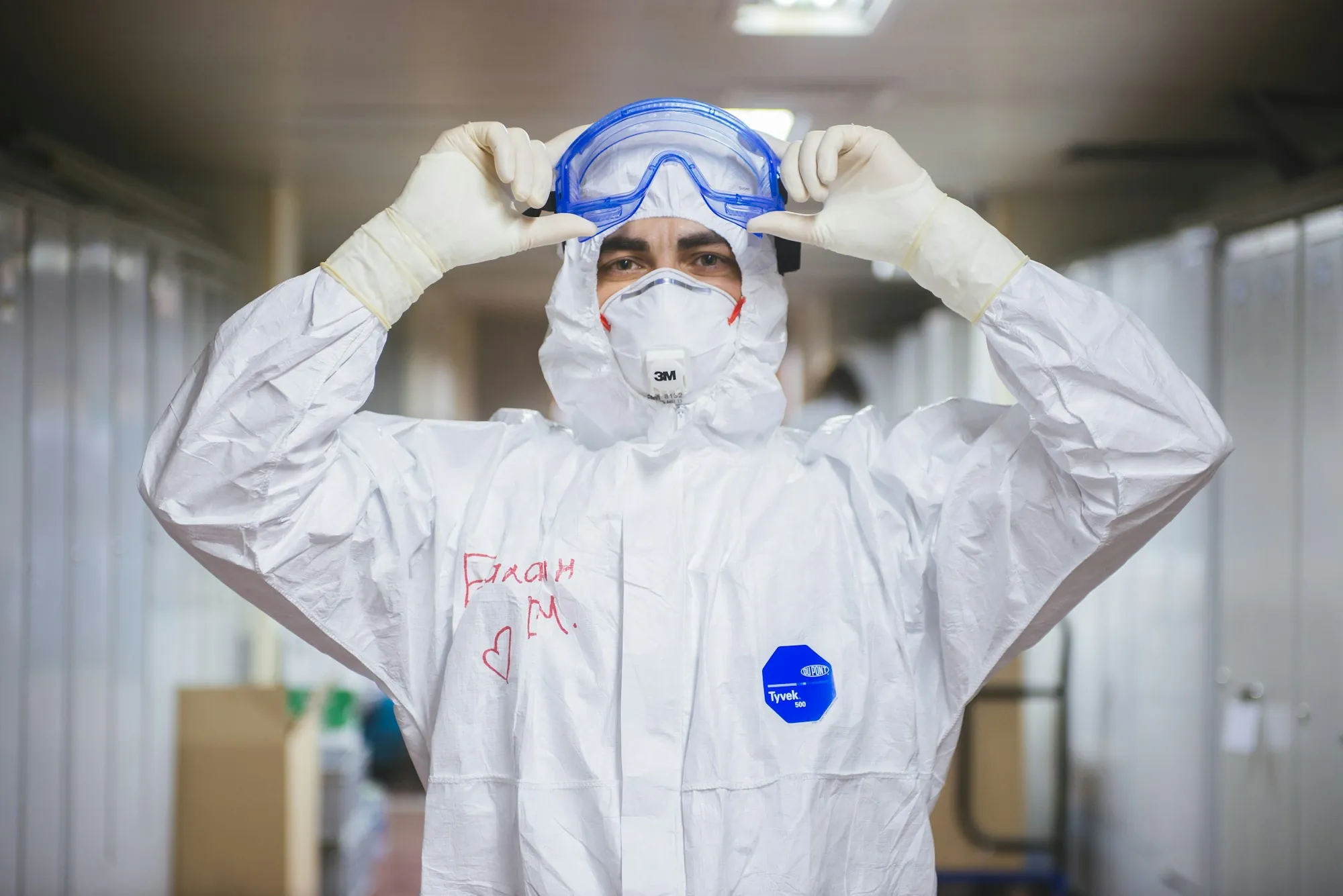 Worker adjusting goggles over a protective suit and respirator