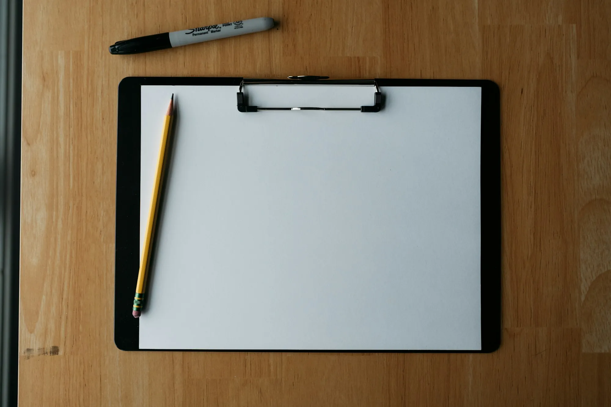 Clipboard and pencil on a wooden desk